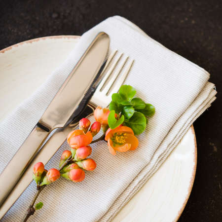 Vintage table setting with delicate flowers on a linen napkin on a dark background, close-up. Holiday Table Set with floral decorの写真素材