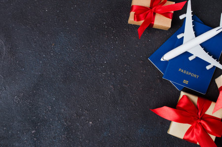 Airplane model, gift boxes and passports on dark background. Travel concept. Top view or flat lay. Copy Space.の写真素材