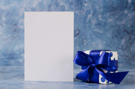 Greeting card for Father's Day or Birthday. Gift box with blank white paper on blue background. Mock up.の写真素材