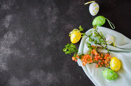 Easter background with decorative Easter eggs and blossoming spring branch on a dark concrete...