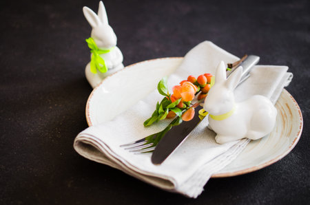 Easter table setting with spring flowering branches, cutlery and decorative rabbits. Spring Easter...