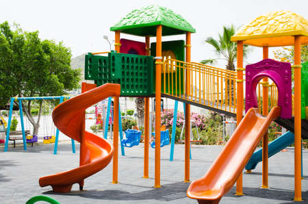 Colorful children playground activities in public park surrounded by green trees.の写真素材