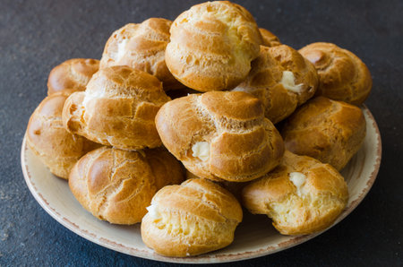 Homemade profitroles pastry filled with custard with tea. Eclairs with cream.