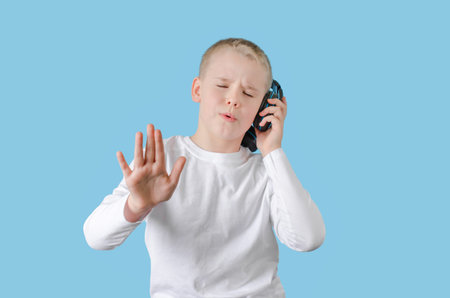 Young child keep your hand on the headphones, enjoying listening to music and sings. Teen boy with...