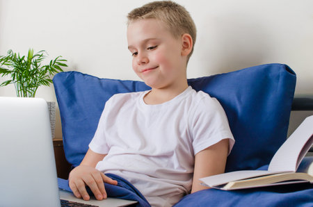 Distance learning and online education concept. Schoolboy studying at home. Boy with laptop lies in...