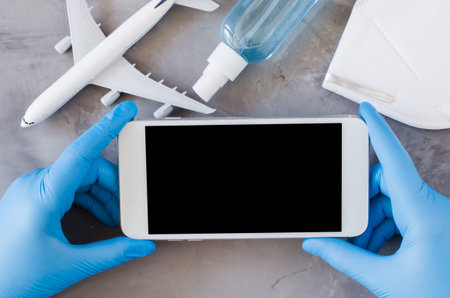 Travel planning concept, coronavirus and quarantine. Hands in disposable gloves hold smartphone....