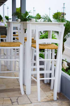 Cozy summer cafe. White tables and chairs on outdoor terrace. Empty street cafe or restaurant.