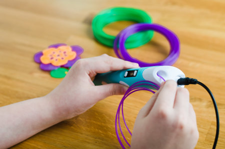 Child using 3D pen. Child inserts ABS plastic in pen to use. Creative hobby at home, technology,...