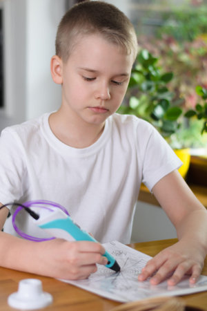 Child using 3D pen. Boy draws on stencil by colored ABS plastic at home. Creative hobby at home,...