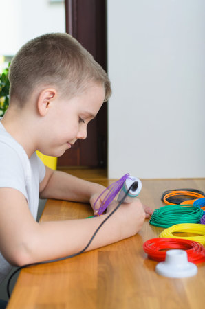 Child using 3D pen. Happy boy making flower from colored ABS plastic. Creative hobby at home, technology, leisure, education concept.の写真素材