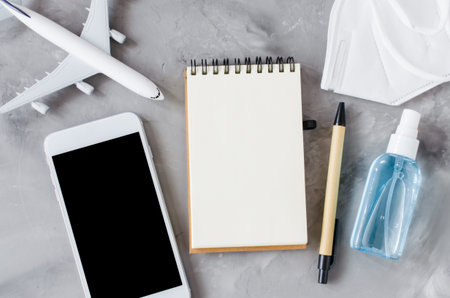 Travel booking concept, coronavirus and quarantine. Mock up of smartphone with notebook and airplane...