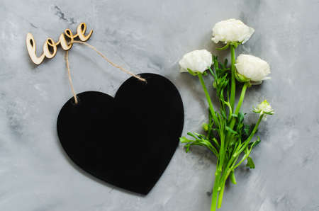 Mock up of greeting card. Empty chalk board heart shaped with flowers and inscription love. Flat lay composition. Top view with copy spaceの写真素材