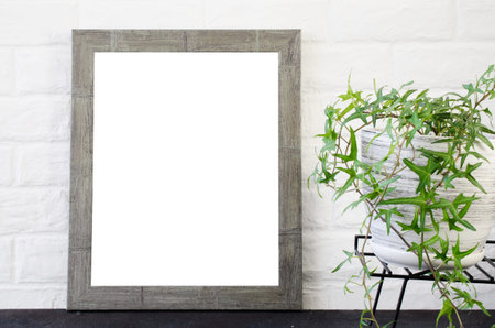 Poster or photo frame and beautiful plant in concrete pot. Scandinavian style room interior. Blank...