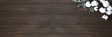 Cotton flower branch on brown wooden background. Cozy autumn and organic lifestyle concept.