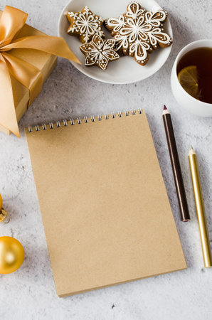 Flat lay of blank brown notebook with gift box, tea and gingerbread cookies. Christmas mock up for greeting card or letter to Santa. Christmas wish list or list to do. Cozy winter mood. Copy space.の写真素材