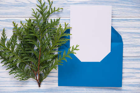Empty Christmas card, envelope with template letter and fir branches on blue wooden background. Mockup for seasonal greetings. Space for text.の写真素材
