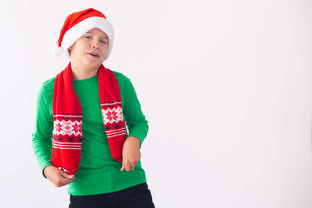 Portrait of happy boy wearing Santa Claus hat and winter scarf on white background. Child having fun at Christmas time. Merry xmas conceptの写真素材