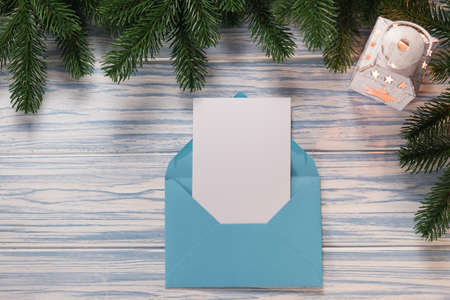 Empty Christmas card, envelope with template letter, latern and fir branches on blue wooden background. Mockup for seasonal greetings. Space for text.の写真素材
