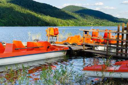 Orange catamarans on lake moored at the pier. Hipster lifestyle. Tourism in national park holiday. Active summer vacation.の写真素材
