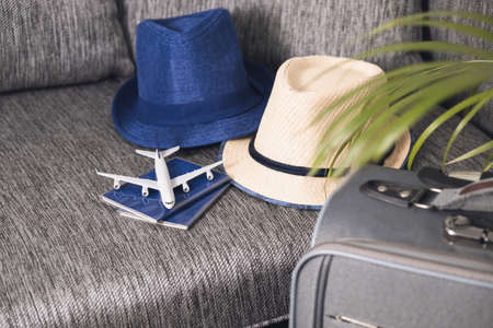 Lifestyle and traveling concept after quarantine Passports, hat and model airplane on gray suitcase Prepairing Air travelの写真素材