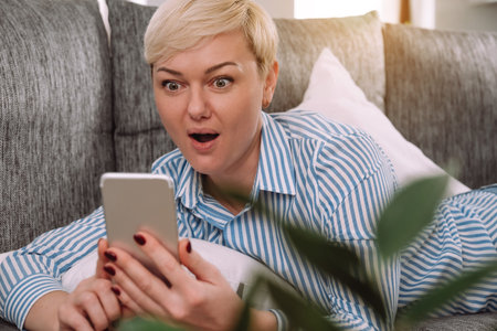 Amazed happy woman feeling great positive surprise reaction, holding smartphone and using mobile app...