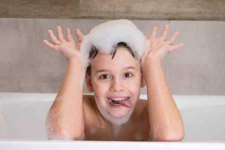 Closeup portrait of funny boy playing with water and foam in bathroom Cute happy child bathe and...
