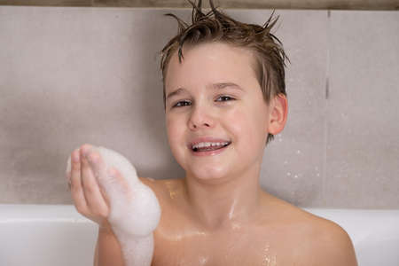 Funny boy playing with water and foam in a bathroom Cute happy child bathe at home healthy childhoodの写真素材
