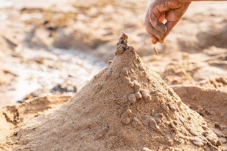Closeup of child hands making sand towers on beach Leisure games with sea sand in summer sunny day...