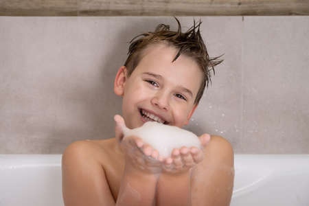 Funny boy playing with water and foam in a bathroom Cute happy child bathe at home healthy childhoodの写真素材