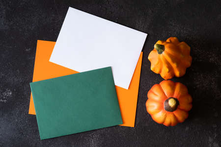 Blank papers in autumn color for mock up template design and decorative pumpkins on dark background.の写真素材