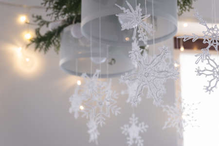 Beautiful winter interior decoration. White knitted snowflakes hang on a chandelier in the Christmas house.の写真素材