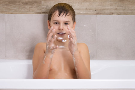 Portrait of boy playing with with soap shampoo or gel in bathroom Child bathe and inflates soap...