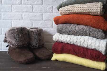 Stack of knitted warm clothes and home shoes. Comfortable cozy things for the home. Autumn and...