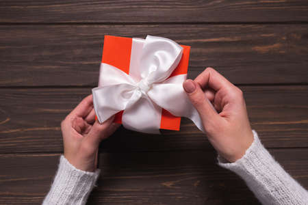 Womens hands untie the white ribbon on Christmas giftの写真素材