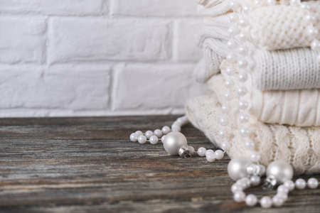 Stack of white cozy knitted sweaters on wooden tableの写真素材