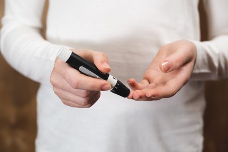 Diabetes checking blood sugar level. Child using lancelet and glucometerの写真素材