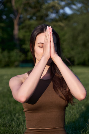 A young woman practices yoga while lying on a mat in the park.の写真素材