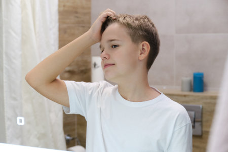 A handsome teenager is enjoying his reflection alone in the bathroomの写真素材