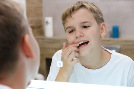Reflection in the mirror of a schoolboy looking at his teeth.