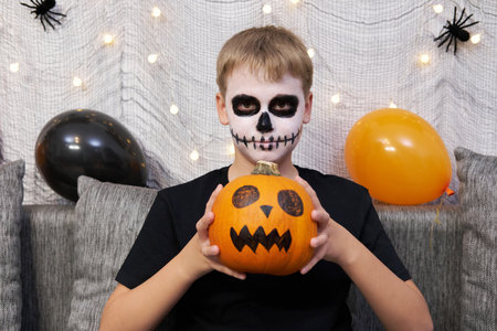 Teenager with makeup on his face and with a pumpkin in his hands for Halloween.の写真素材