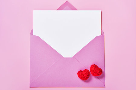 Greeting card mockup, white blank card in an envelope and knitted red hearts.