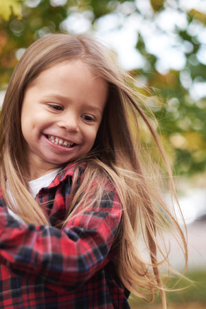 Portrait of cute joyful girl with long hair against background of an autumn tree. Happy childhood.の写真素材
