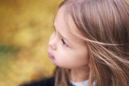 Portrait of cute joyful girl with long hair against background of an autumn tree. Happy childhood.の写真素材