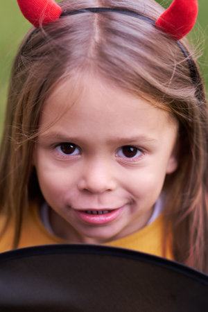 Portrait of girl in a Halloween devil costume with horns. Happy childhood. All Saints Day.の写真素材
