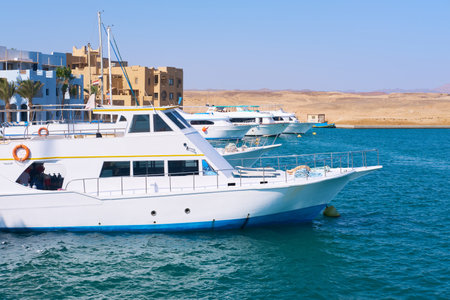 White yacht anchored in clear blue waters near a coastal resort on a sunny dayの写真素材