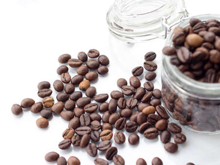 heap of coffee beans isolated on a white background from glass jarの写真素材