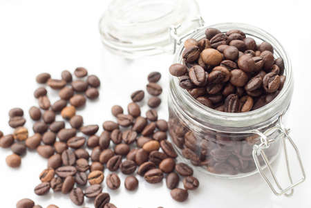 heap of coffee beans isolated on a white background from glass jarの写真素材