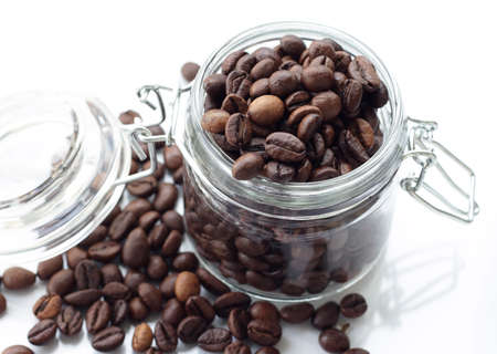 heap of coffee beans isolated on a white background from glass jarの写真素材
