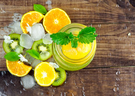 Citrus fruit and herbs water for detox or dieting in glass bottles on wooden board, dark background, selective focus, square crop. Clean eating, weight loss, healthy lifestyle conceptの写真素材
