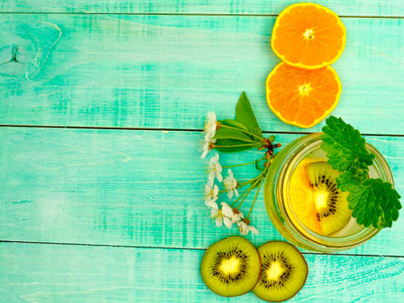Citrus fruit and herbs water for detox or dieting in glass bottles on wooden board, blue background, selective focus, square crop. Clean eating, weight loss, healthy lifestyle conceptの写真素材